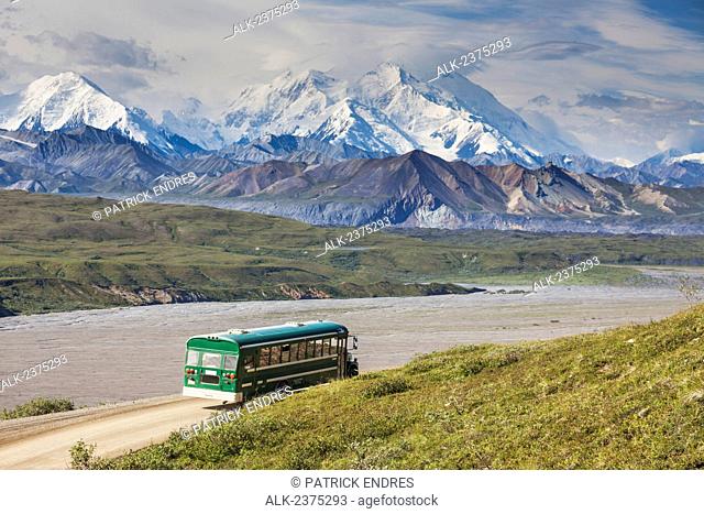 Tour bus of park visitors travel the Denali Park road along the Eielson Bluffs, Denali National Park, interior, Alaska