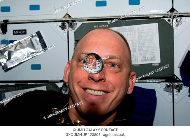 NASA astronaut Clayton Anderson, STS-131 mission specialist, watches a water bubble float freely between him and the camera, showing his image refracted
