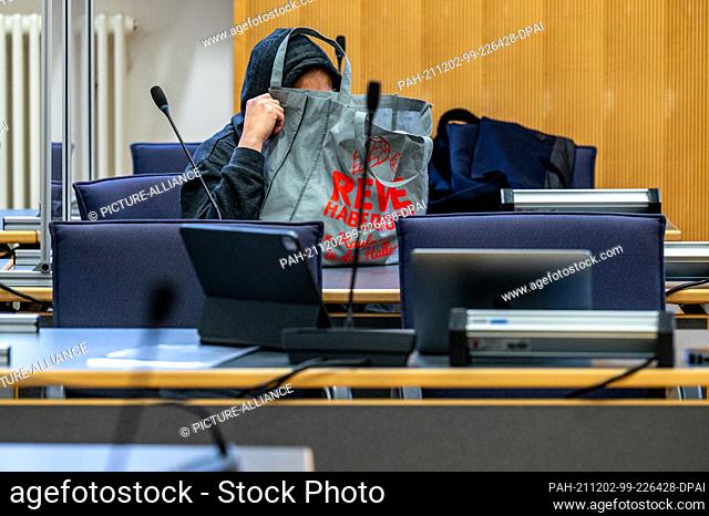 02 December 2021, Bavaria, Regensburg: The defendant sits in the courtroom of the regional court and holds a bag in front of her face