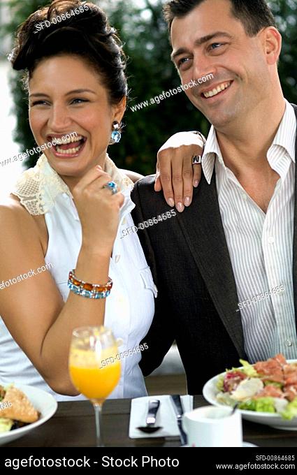Couple sitting at outdoor restaurant table with meal