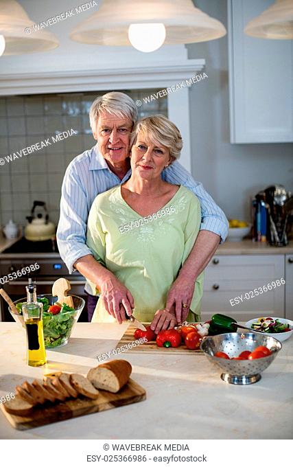 Happy senior couple cutting vegetables in kitchen
