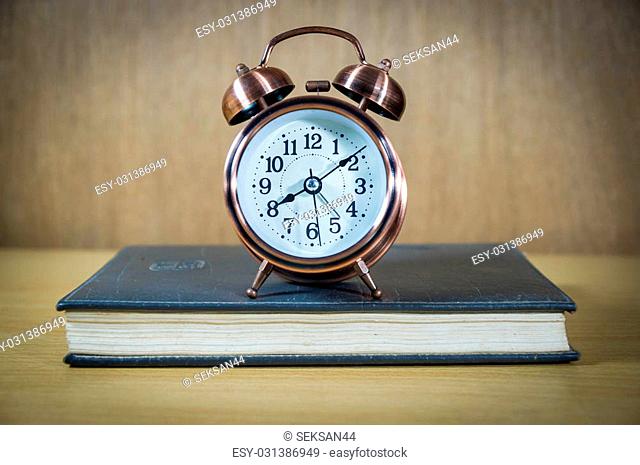 Vintage background with retro alarm clock and book on table