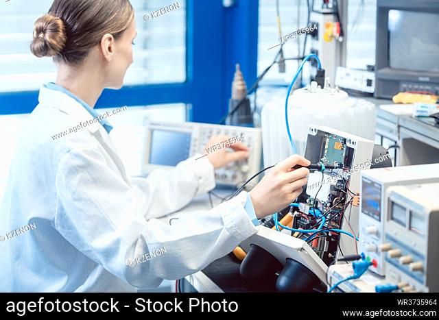 Engineer woman measuring electronic product on test bench in her lab for EMC compliance