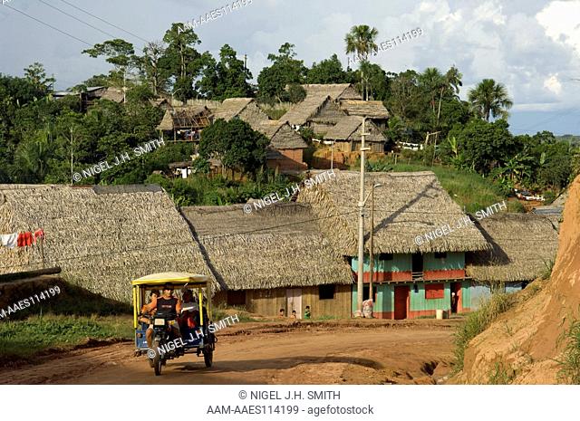 Houses thatched with sheb?n (Attalea butyracea) palm fronds. Aguaje (Mauritia flexuosa) in home gardens. Motcarro (motor cycle taxi) with passengers in an...
