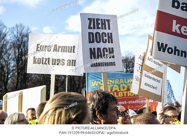 09 December 2019, Berlin: Signs with the inscription ""Eure Armut kotzt uns an"" and ""Zieh doch nach Brandenburg"" are held up in front of the Brandenburg Gate...