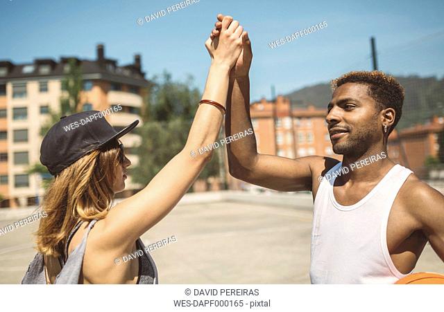 Young couple giving high five on basketball court