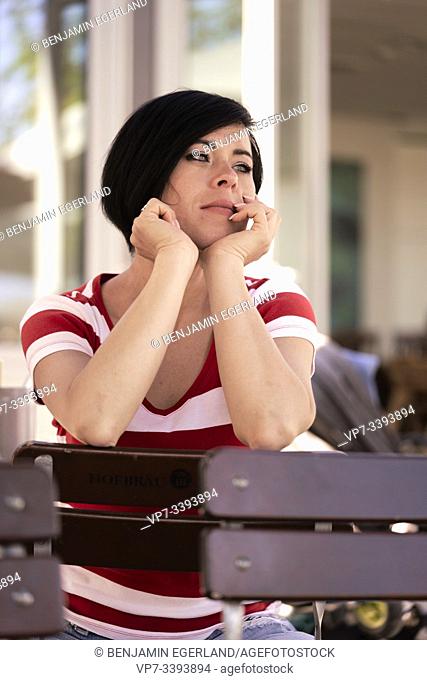thoughtful woman sitting on chair outdoors, in Bavaria, Germany