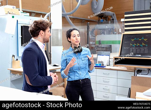 Male and female entrepreneur discussing while standing in factory