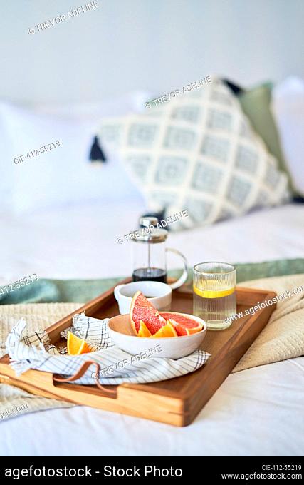 Grapefruit and coffee breakfast tray on morning bed