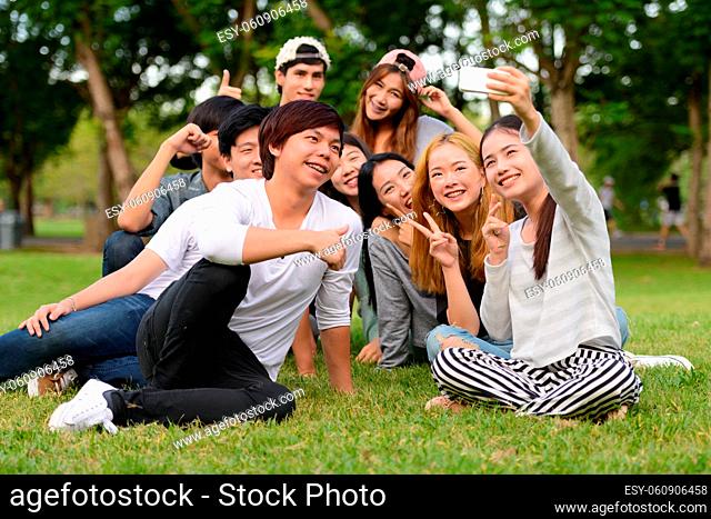 Group of young Asian friends hanging out and relaxing together at the park outdoors