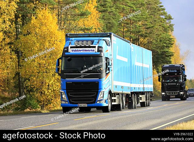 Blue Volvo FH heavy truck of Veka-Trans pulls trailer along highway flanked by trees in autumn colours. Salo, Finland. October 11, 2019