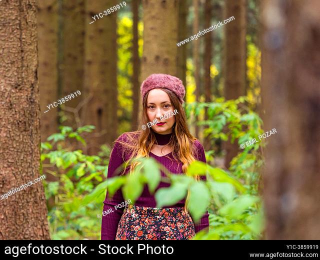 Close-up young woman in Autumn in a forest looking at camera