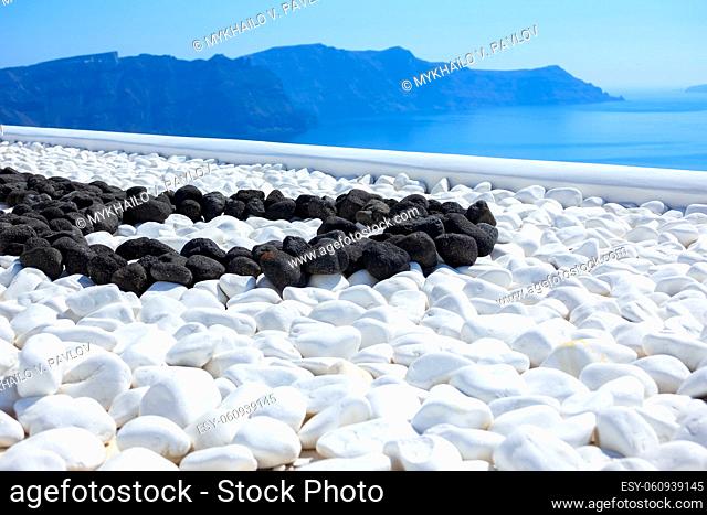 Greece. Thira island. Sunny day in Santorini. Black and white stones on the terrace with sea view