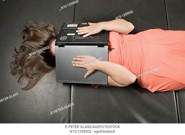 Young woman lying on a mat, a laptop computer covering her face