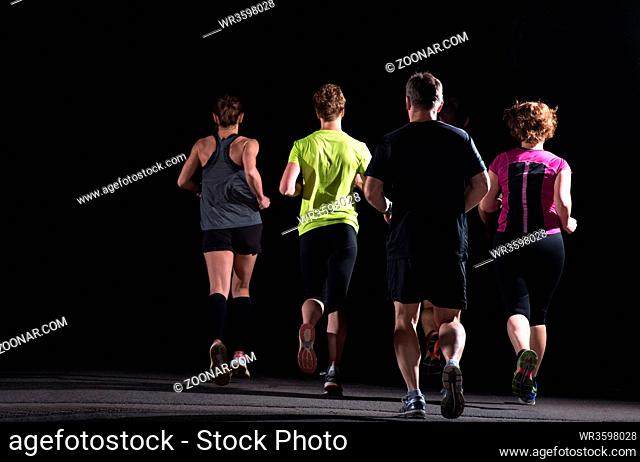 group of healthy people jogging in city park, runners team at night training