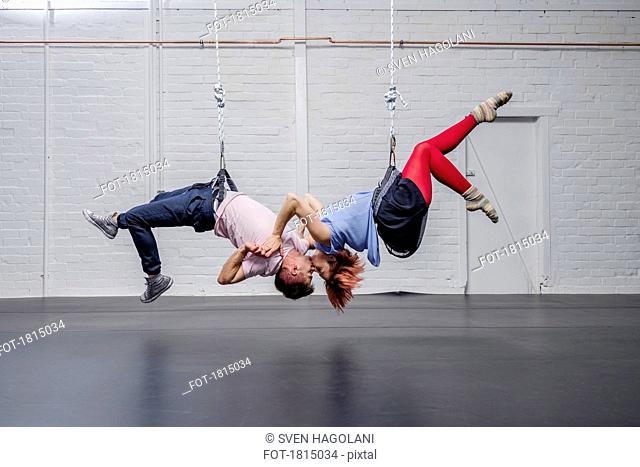 Modern aerialist dancers performing, hanging upside-down and kissing