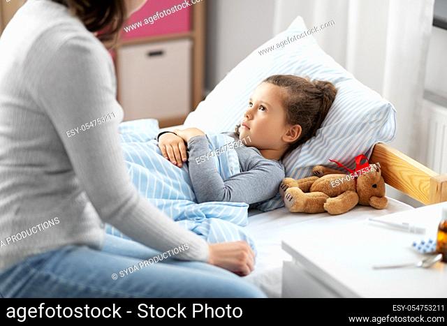 mother and sick daughter lying in bed at home