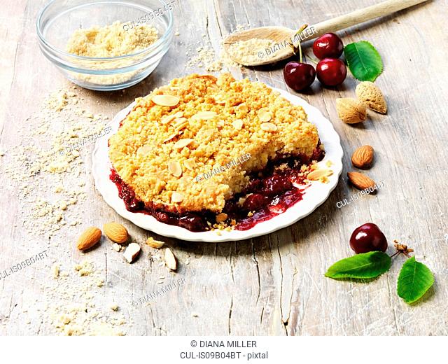 Sour cherry and almond crumble pudding, almonds, cherries, white washed rustic wooden table