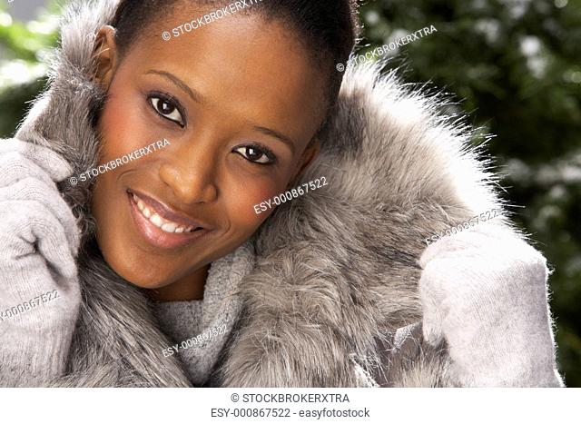 Fashionable Woman Wearing Fur Coat In Studio In Front Of Christmas Tree