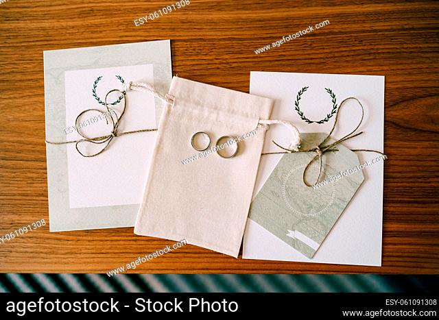 Gold wedding rings on a fabric bag between the leaves with the vows of the bride and groom. High quality photo