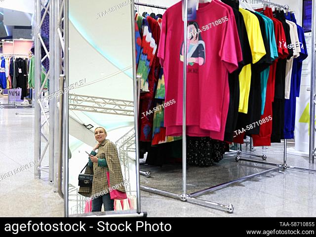 RUSSIA, MOSCOW - APRIL 28, 2023: A woman is reflected in a mirror as she tries on a piece of clothing during the Moscow Fashion Week at the Oceania Shopping...