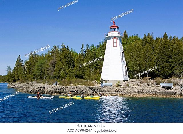 Kayakers paddle past the Big Tub Lighthouse, Fathom Five National Marine Park, Ontario, Canada