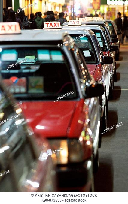 The typical red taxis queueing up idle at a taxi stand in Wanchai (Wan Chai) in the night, Hong Kong Island, Hong Kong, China, Southeast Asia