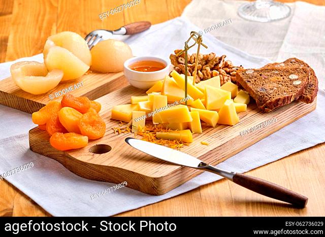 Set of various appetizers for wine - cheese, walnuts, dried apricots, honey and canned pear