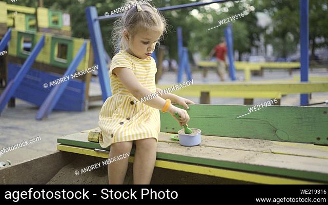 Cute little girl is playing in the sandbox on the playground. Child girl playing on the playground in the city park