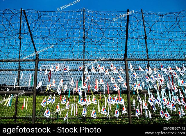 Fence with barbed wire and south korean flags at the demilitarised zone DMZ at the freedom bridge with blue sky, South Korea, Asia