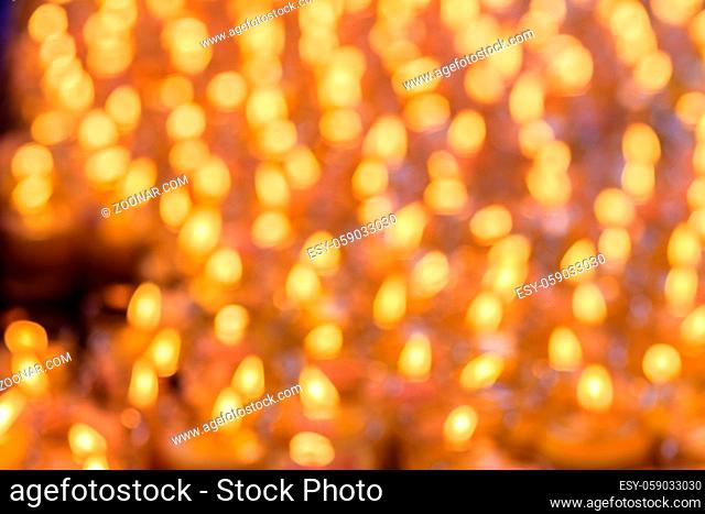 Beautiful blurred orange bokeh light of many candles, un-focus bokeh of the candle with dark background. Orange bokeh light of many candles in religious...