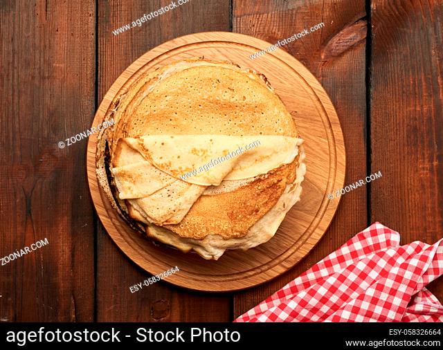 fried round pancakes on a wooden board, brown table, top view