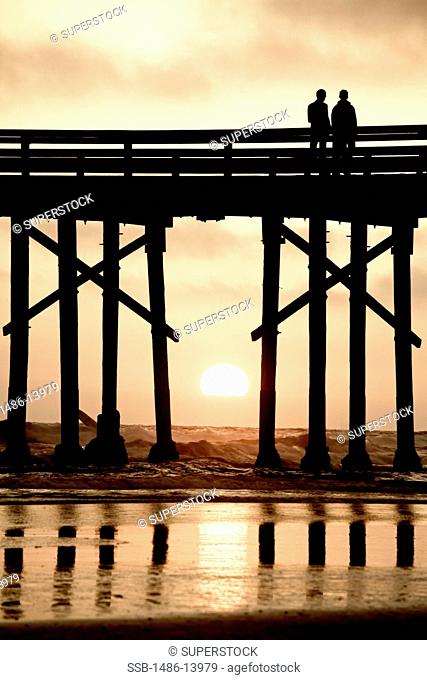 Silhouette of people standing on a pier, Newport Beach, Orange County, California, USA
