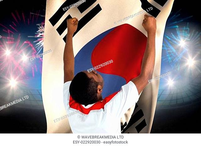 Excited handsome football fan cheering against fireworks exploding over football stadium and korea republic flag