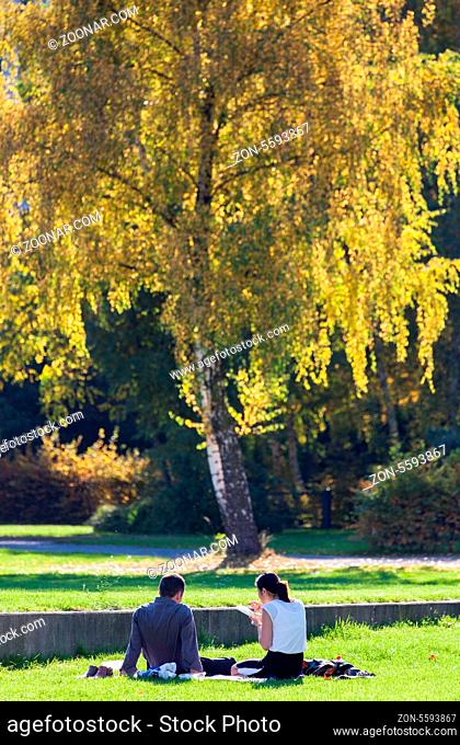 Paar sitzt während der Mittagspause bei herbstlicher Sonne im Park