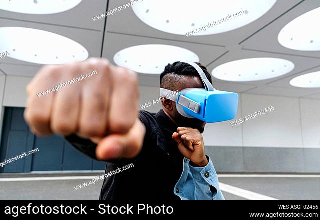 Man boxing wearing virtual reality headset under illuminated ceiling