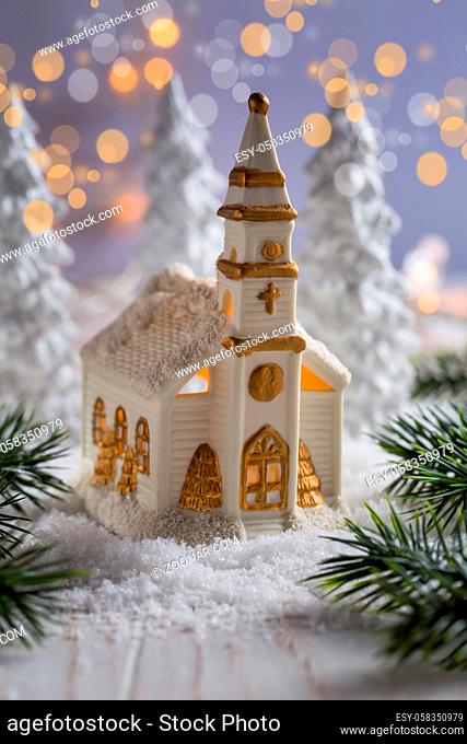 Small church with candles and white trees as snowy landscape. Christmas decoration. Symbol of Christianity