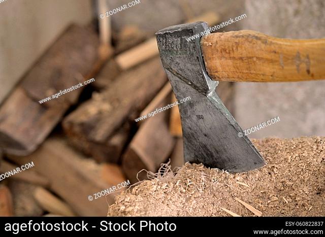 Ax in a wooden block with logs in the background