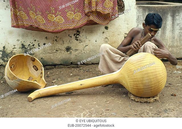 Instrument maker finishing a veena, a traditional stringed instrument consisting of a hollow wooden body and long neck