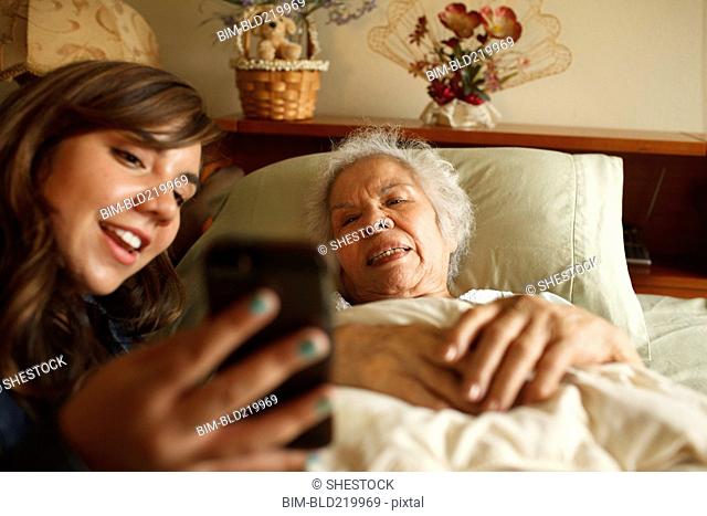 Grandmother and granddaughter taking selfie with cell phone in bed