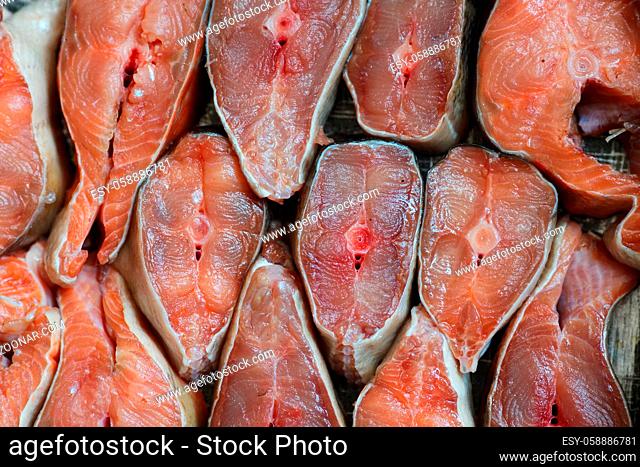 Sliced pieces of red fish are arranged in a row. Abstract background of chum salmon or pink salmon close-up. Backdrop for fish products