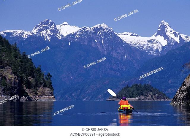 Sea kayaker at Prideaux Haven, Desolation Sound, Coast Mountains in background, British Columbia, Canada