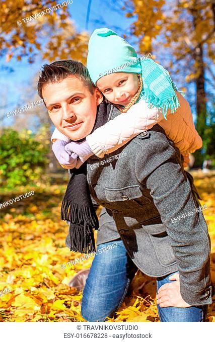 Adorable little girl with happy father having fun in autumn park on a sunny day