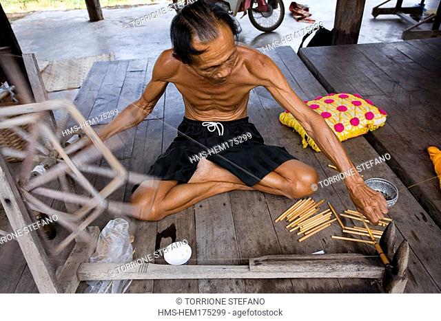 Thailand, Northeastern Thailand, Isan region, Chaiyaphum province, Ban Khwao, specialised centre in silk manufacture, man weaving silk threads with ancient and...