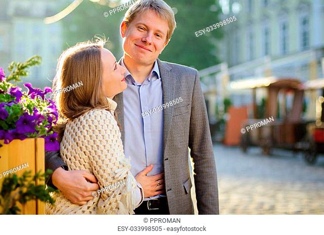 Young fashion elegant stylish couple stand opposite each other on streets of european city in summer morning