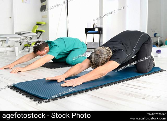 Therapist with protective face mask Assisting patient With Stretching Exercises. High quality photo