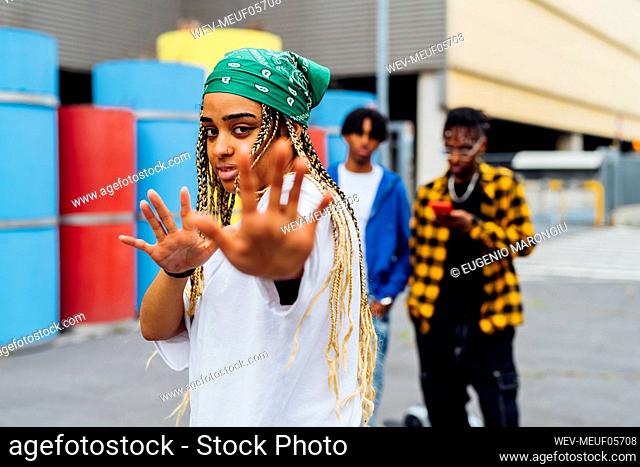 Woman wearing bandana gesturing hands standing in front of men