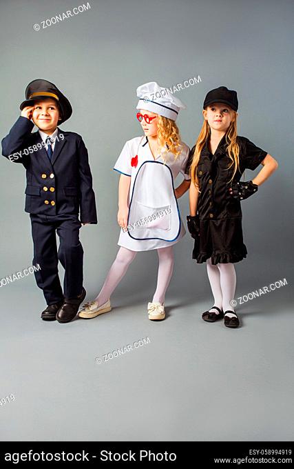 The little kids are dressed in different costumes of job. The children demonstrate the profession of pilot, doctor and officer