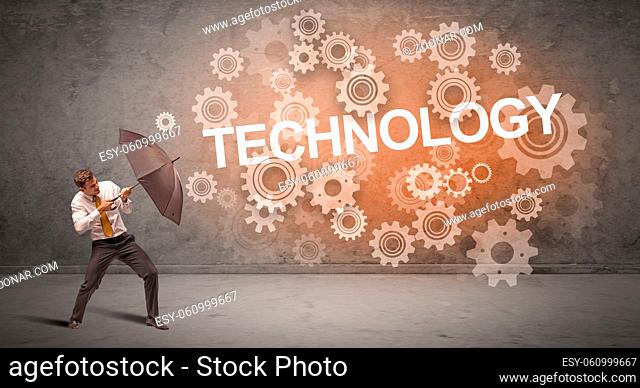 Businessman defending with umbrella from TECHNOLOGY inscription, technology concept