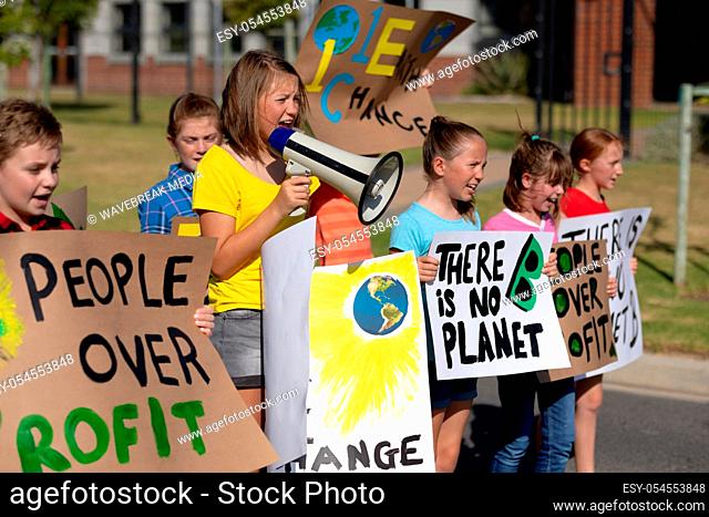 Side view of a group of Caucasian elementary school pupils on a protest march, carrying signs with environmental and conservation slogans on them